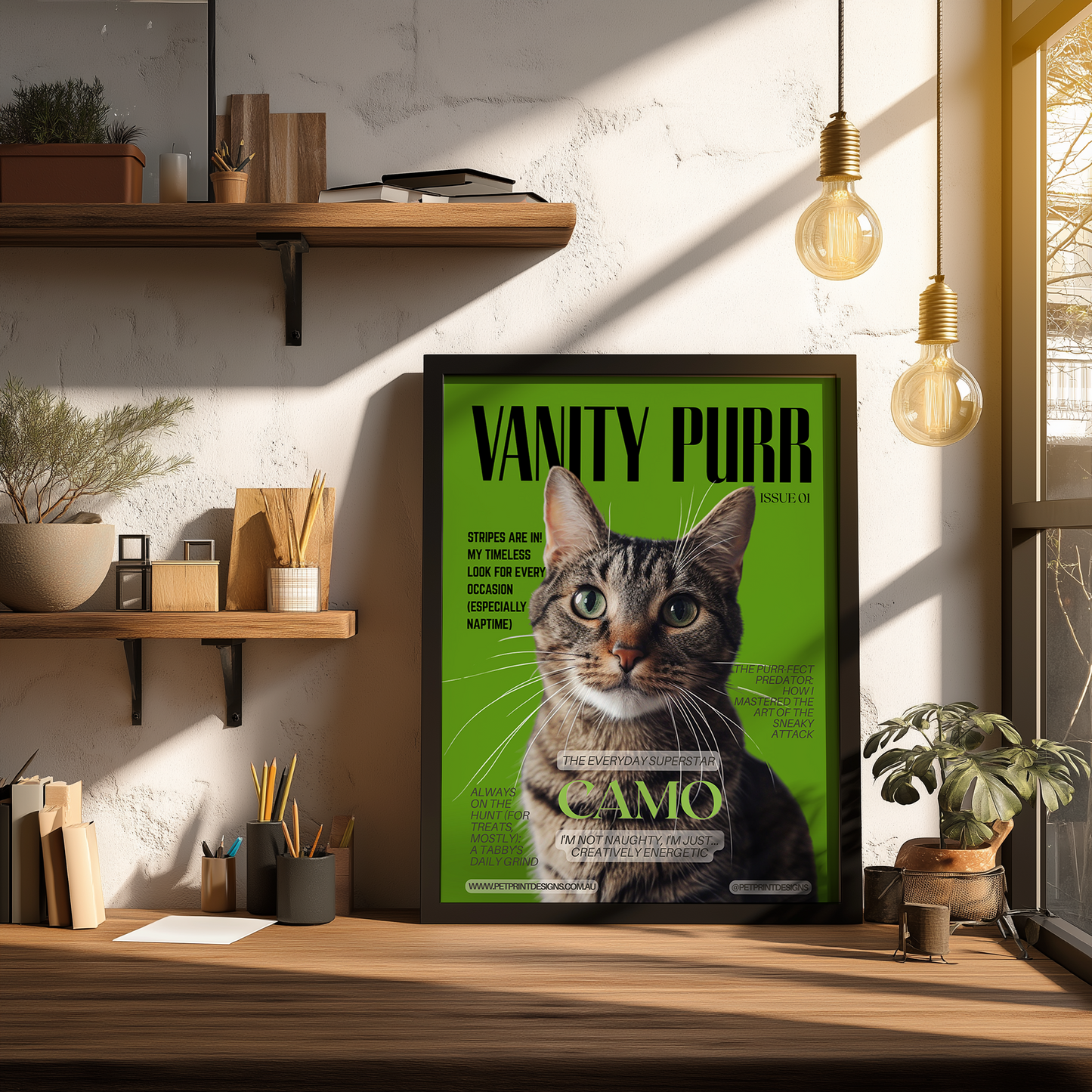 Framed poster of a cat with 'Vanity Purr' text on a green background, placed on a wooden desk.