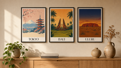Three framed prints of Tokyo, Bali, and Uluru on a wall above a wooden shelf with decorative items.